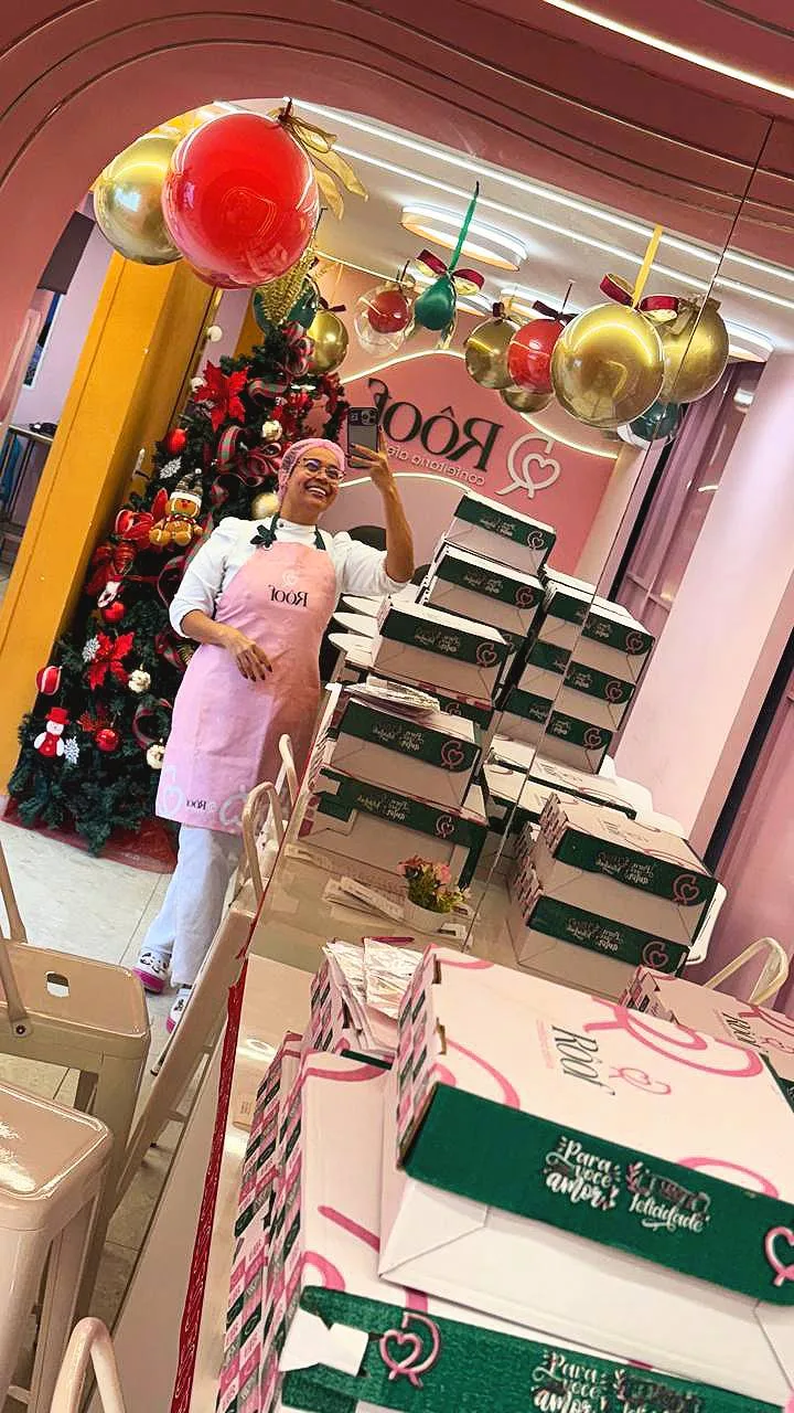 Rosi França na loja da Rôof decorada de Natal, com pilhas de caixas de encomendas prontas
